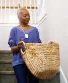 Woman walking down stairs with woven laundry basket