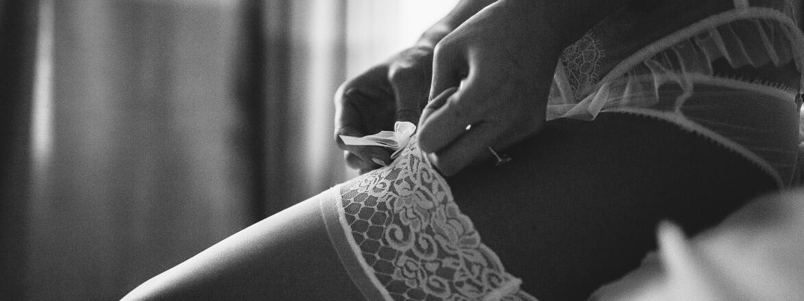 Boudoir photo shoot with woman in lingerie and showing garter on her thigh 