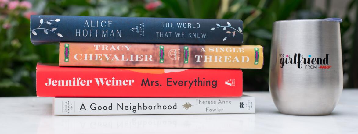 Stack of Books on a white table outside with a girlfriend stemless wine glass.