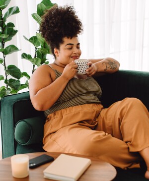 Woman sitting out couch relaxing and drinking coffee