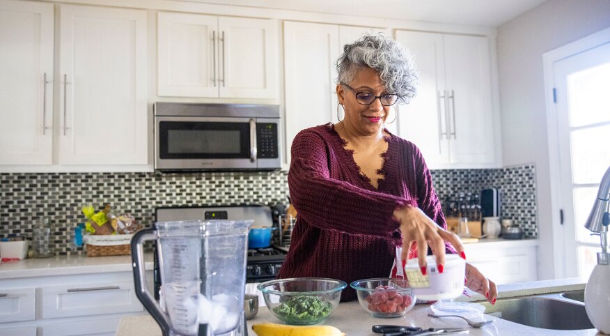 Woman in kitchen making a smoothie