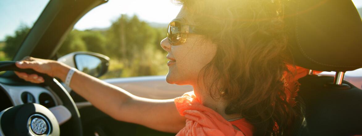 Woman driving in a convertible at sunset