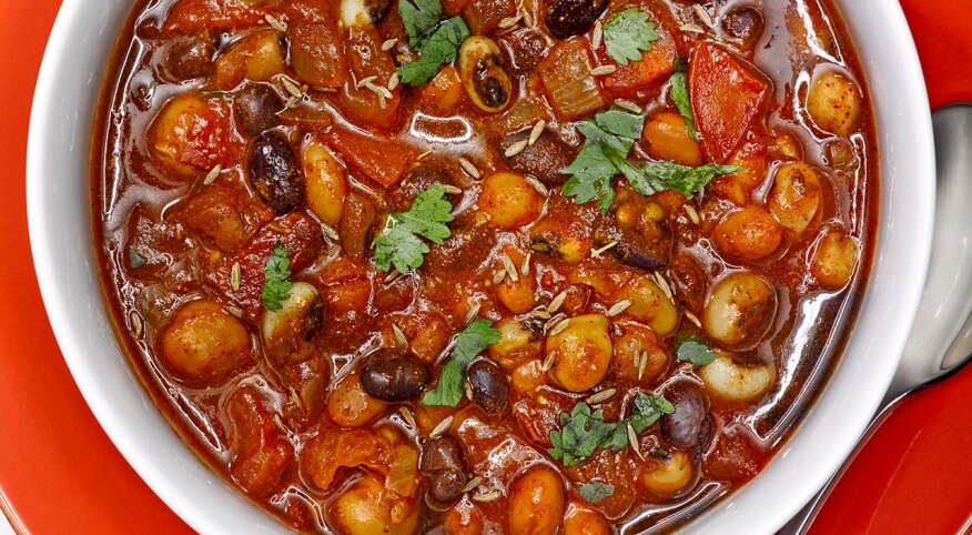 Close up of bean chili with garnish in a white bowl