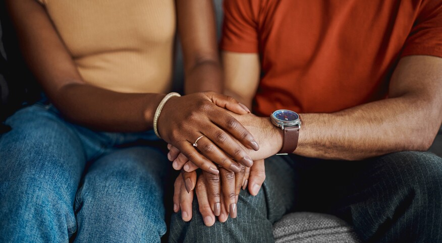 Close-up couple sitting together on the sofa at home and holding hands