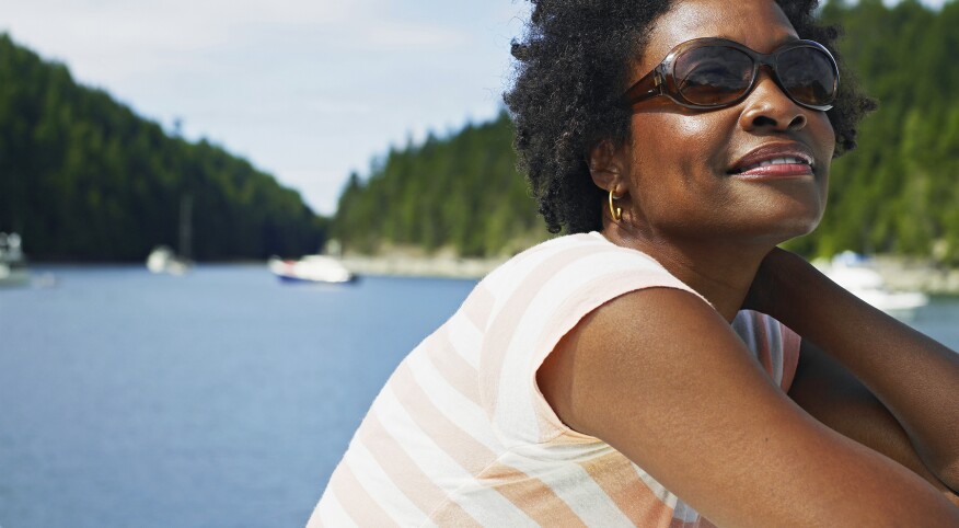 Mature woman in sunglasses sitting on deck of yacht,smiling
