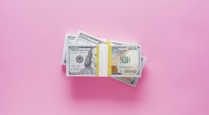 stacks of 100 dollar bills on pink background
