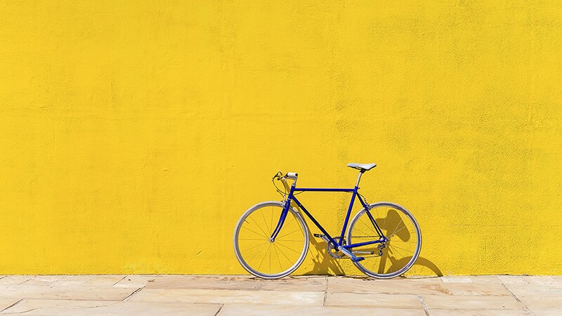 A bicycle parked on a sidewalk against a wall