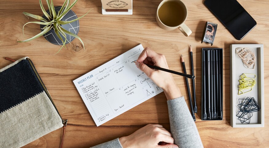 Overhead Shot Of A Small Business Owner Writing In Weekly Planner