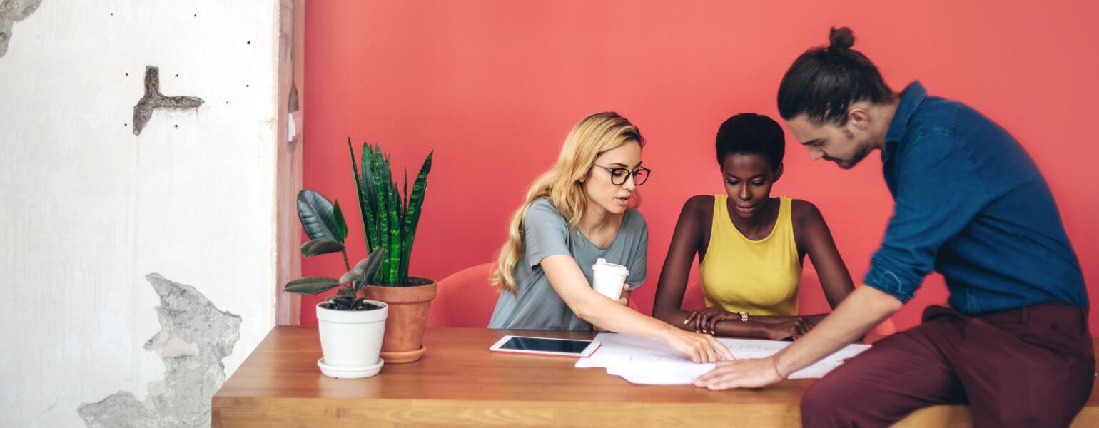 Two women and a man reading paperwork at a desk