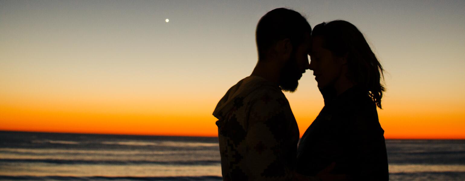 couple embracing in front of sunset