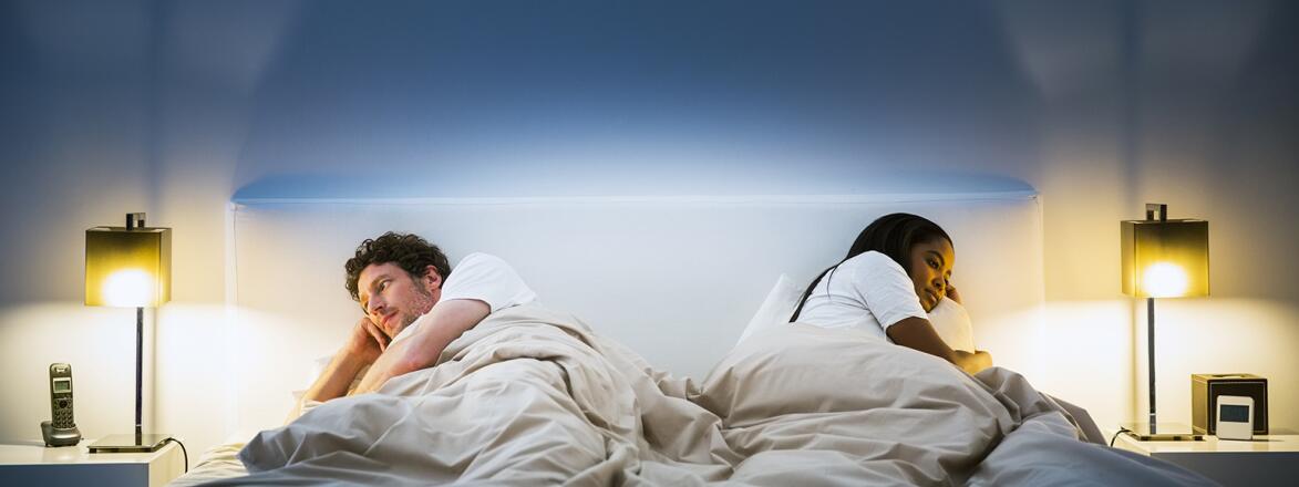 couple lying in bed facing opposite directions