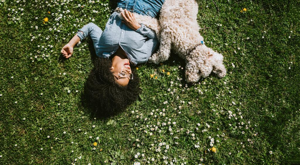 A Young Woman Rests in the Grass With Pet Poodle Dog