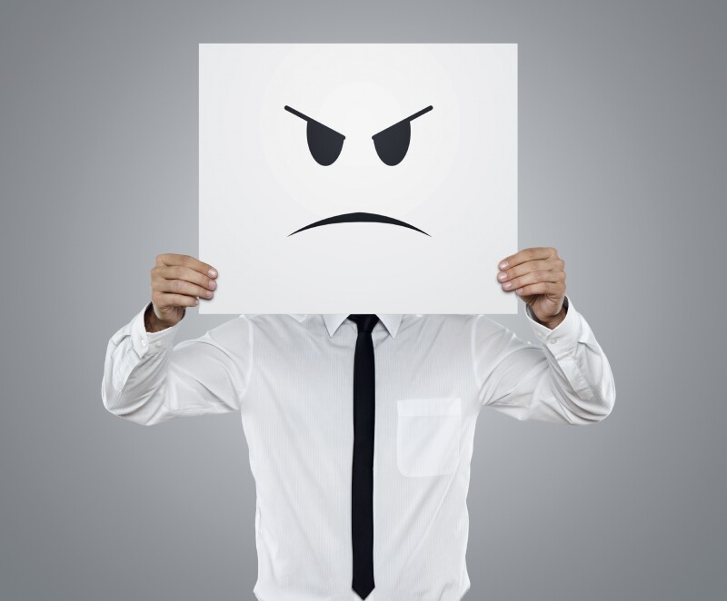 Young businessman holding card with a angry face on it isolated