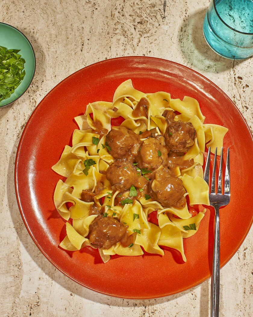 Swedish meatballs with egg noodles on an orange plate