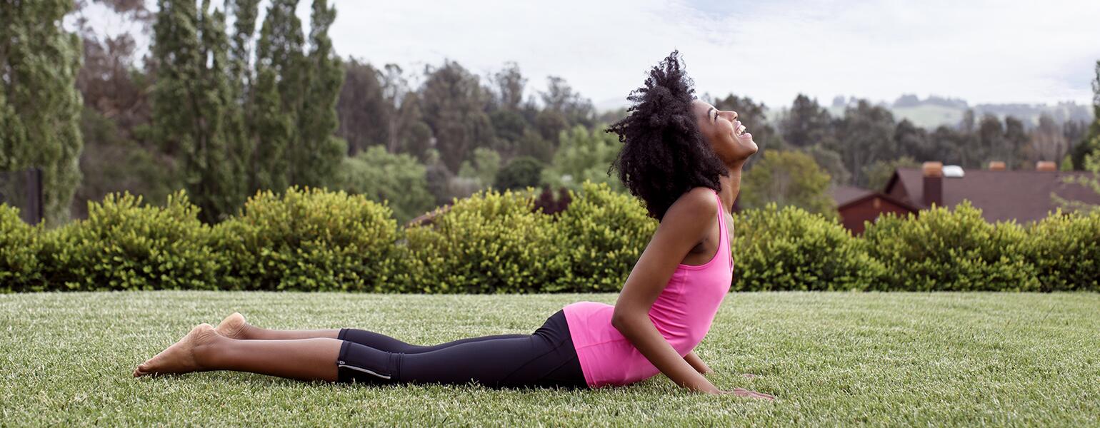 Woman doing yoga outside to help with perimenopause pain.