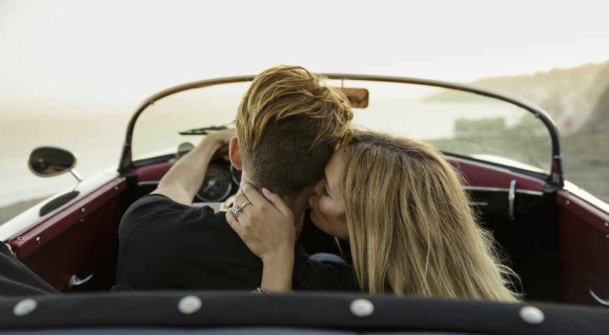 A woman kissing her partner's neck while in a car.