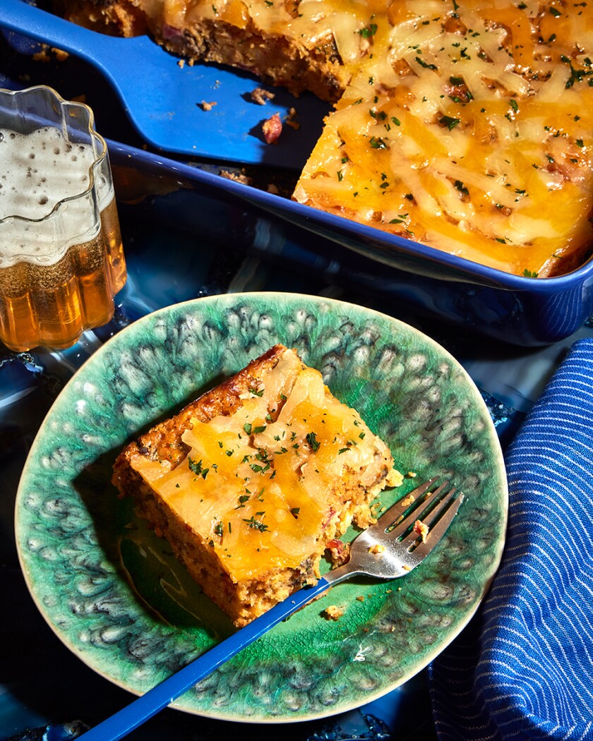 Mexican beef and cornbread with cheese crust casserole on green plate with casserole in blue dish in background