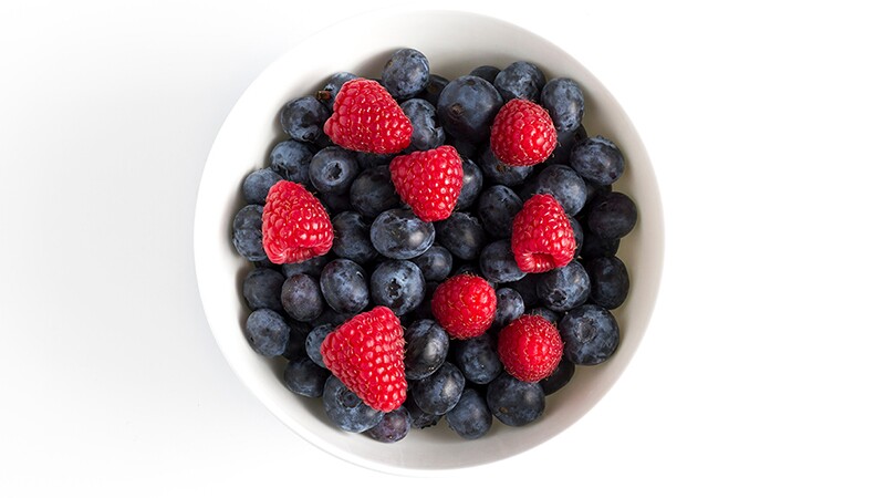 A bowl of blueberries and strawberries against a white background