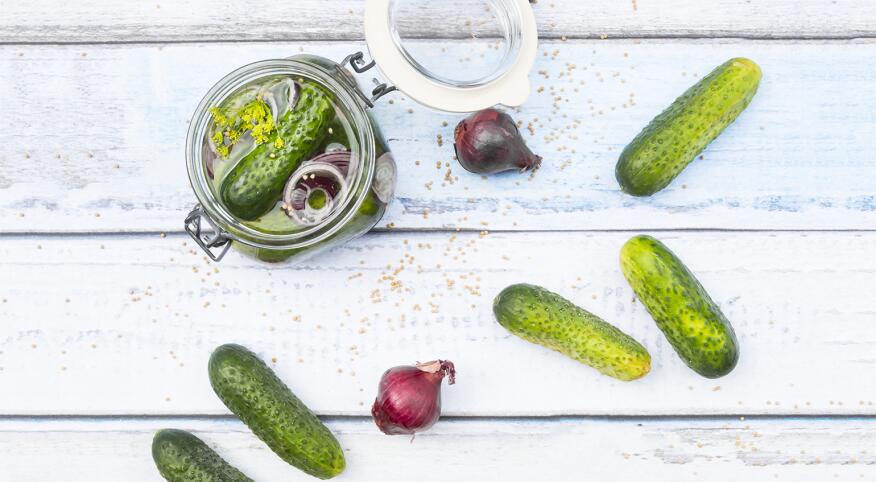 Photograph of pickles in a jar with pickle juice.