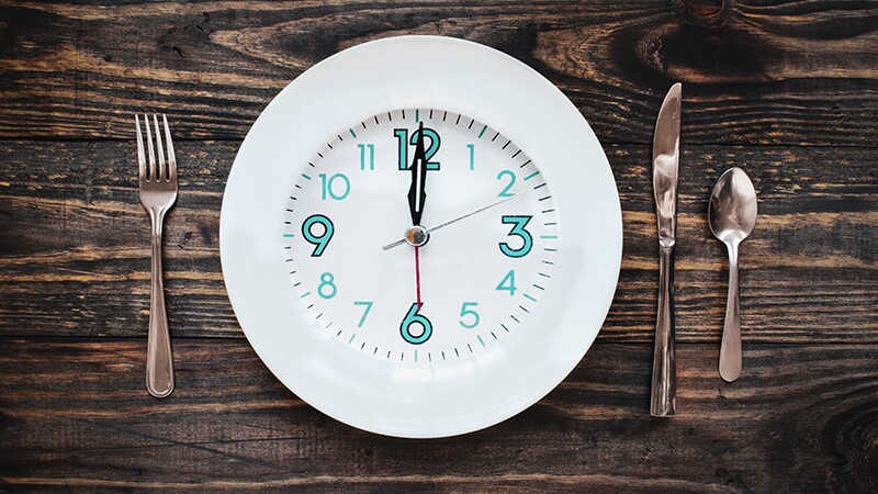 A clock in the form of a plate on a rustic wooden table