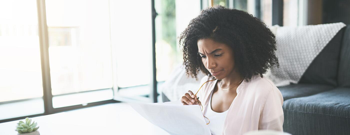 Woman sitting at table looking over finances