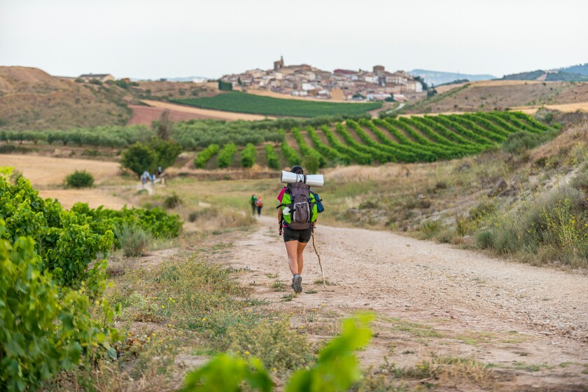 A pilgrim hiking the trail called Camino de Santiago also known as The Way towards the beautiful little village of Cirauqui