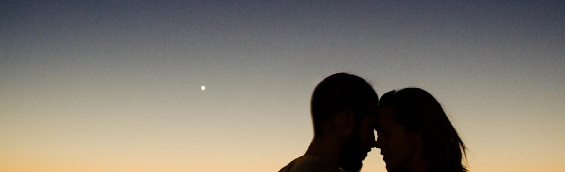 couple embracing in front of sunset
