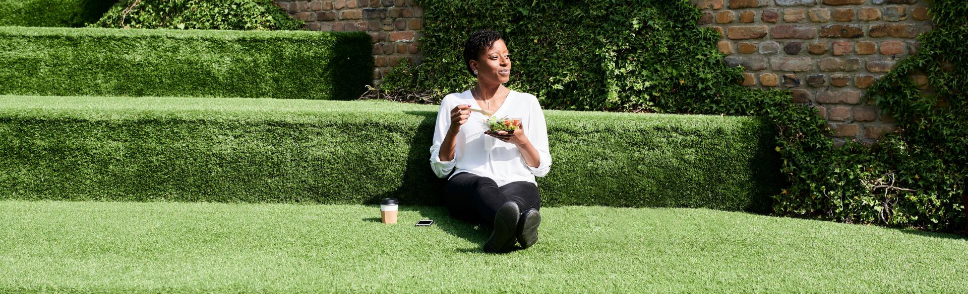 A woman practicing mindful eating sitting in the grass