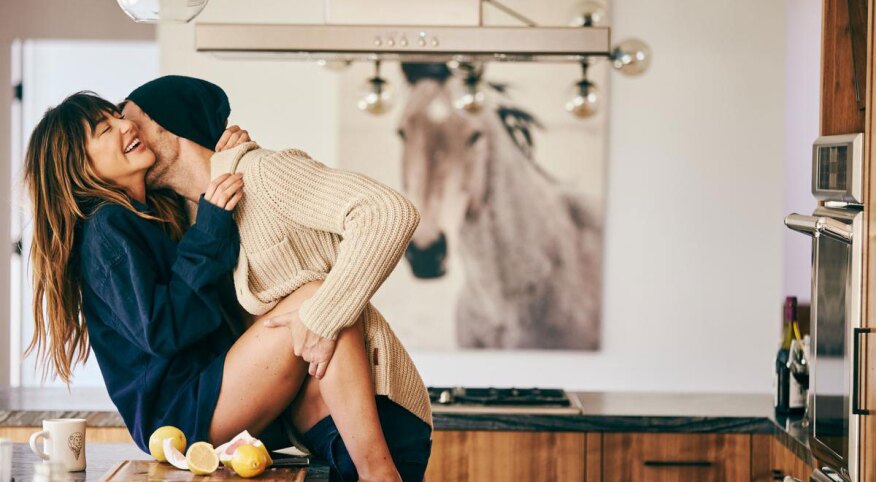 Woman on the kitchen countertop with a man kissing her neck