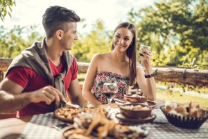 Young couple having lunch in outdoor restaurant during a culinary travel