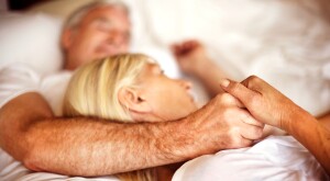 Mature couple in bed holding hands