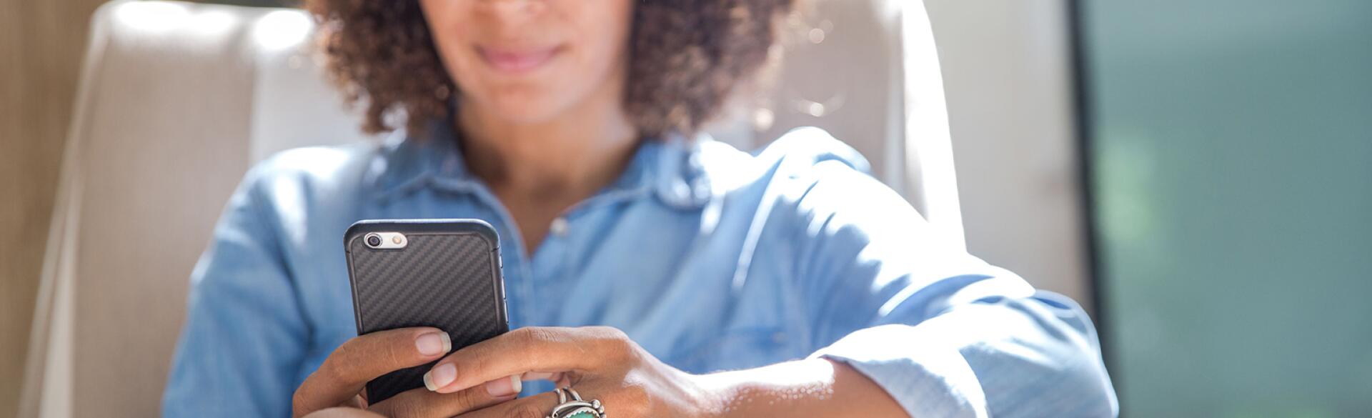 Woman Relaxing At Home While Reading On Her Smartphone