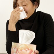 Woman sneezing into tissue