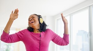 Woman in headphones singing and dancing in her home