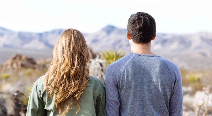Male and female friends overlooking mountain scenery.