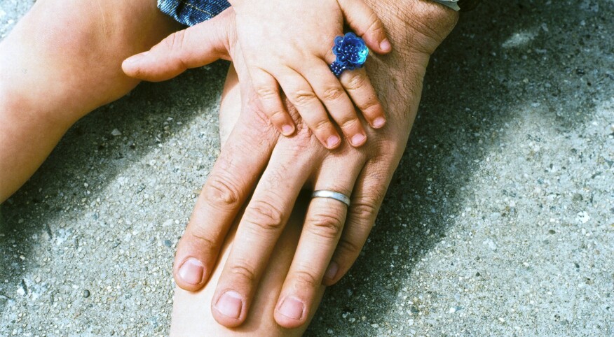 small toddler hand on top of her fathers hand