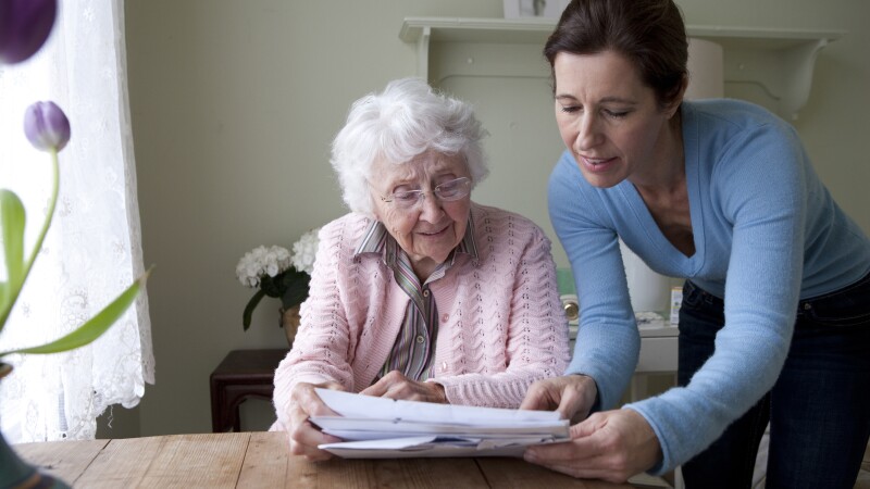 Woman reading to mother at table
