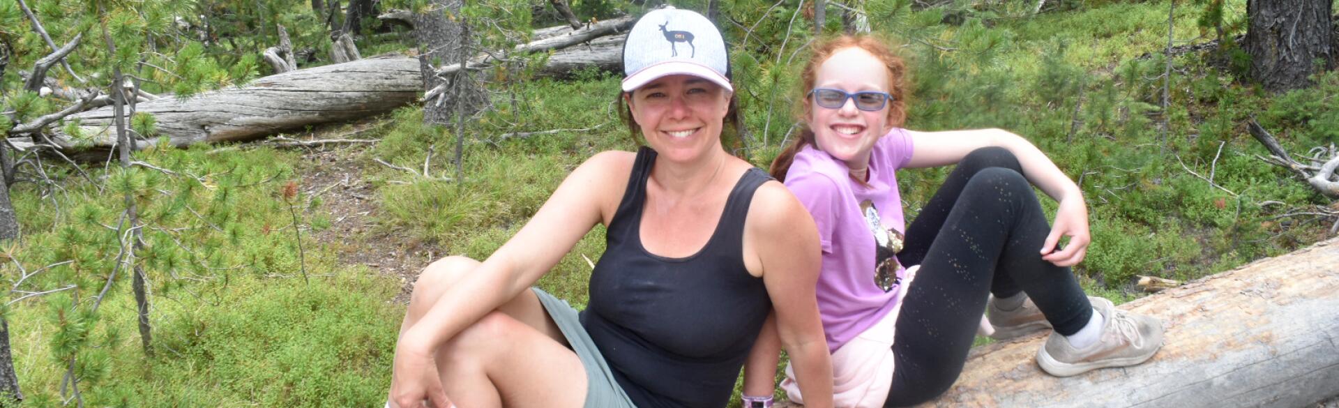 photo of author and her daughter outside hiking sitting on a log