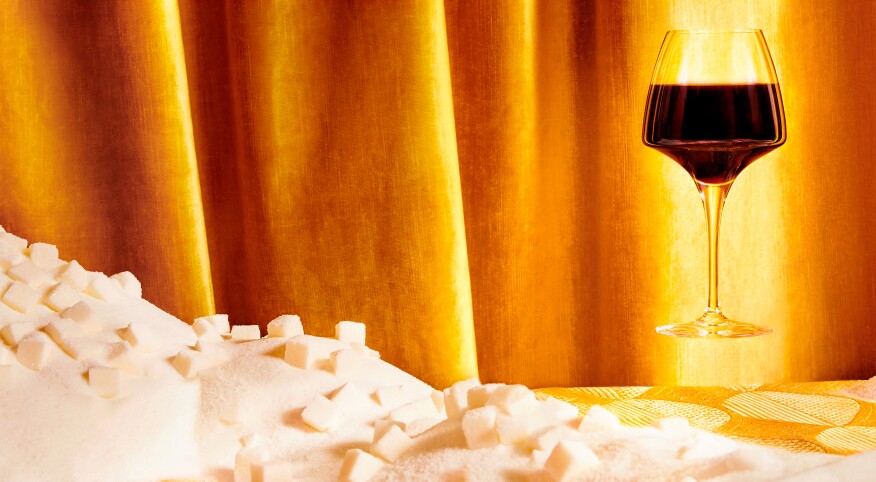 Glass of red wine hovering over mountain of sugar cubes