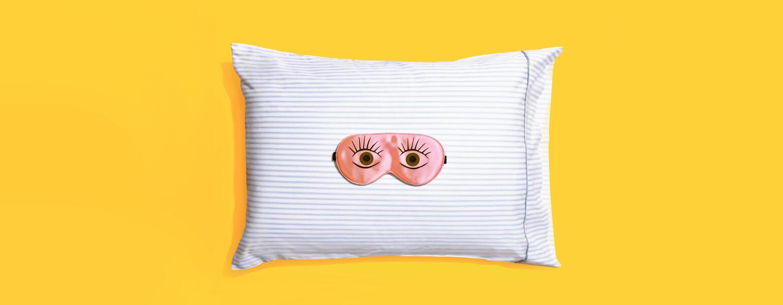 Sleeping mask on a striped pillow and yellow background