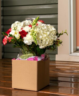 A box with a flower bouquet on a front porch in front of the door