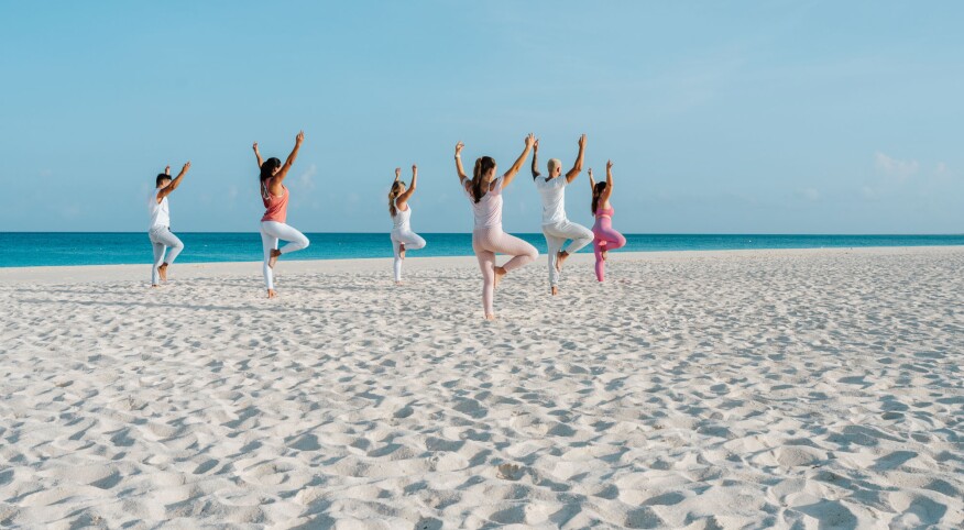 Women on a beach doing yoga at Bucuti & Tara in Aruba