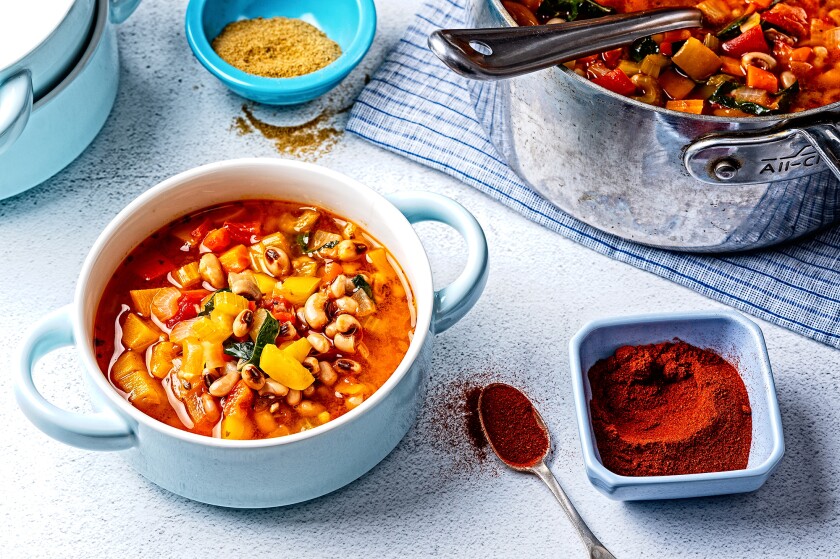 Black eyed pea soup recipe beside paprika on a blue background for a healthy New Year