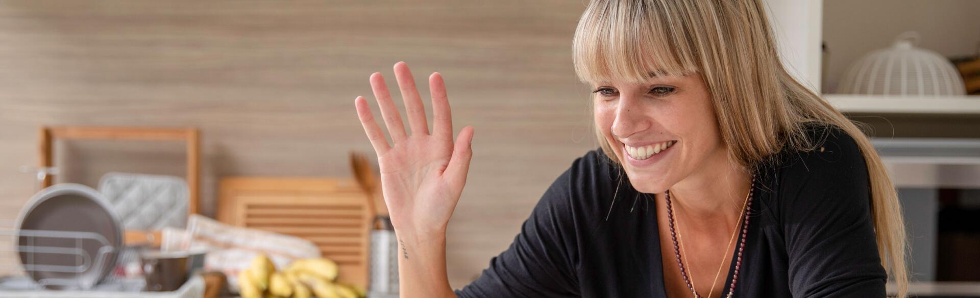 Woman-video-chatting-with-friend-while-cooking-in-kitchen-waving-Stocksy_2862004-612.jpg