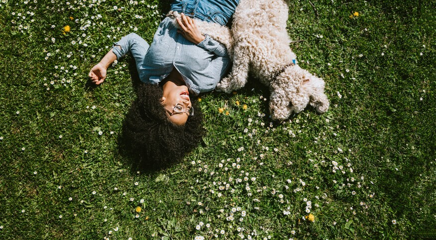 A Young Woman Rests in the Grass With Pet Poodle Dog