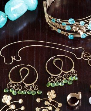Gold jewelry with blue and green gemstones on dark brown wood surface