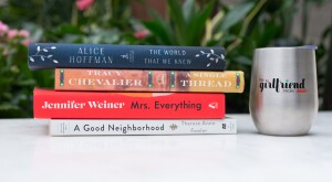 Stack of Books on a white table outside with a girlfriend stemless wine glass.