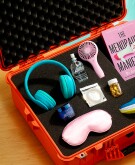 Various items including lube, sneakers, a fan and sleep mask in a safe foam case sitting on a table at home