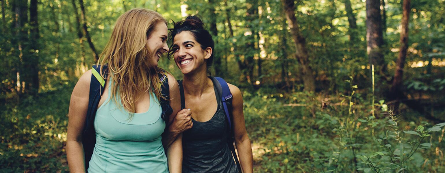 Two women best friends on a hike in the woods.
