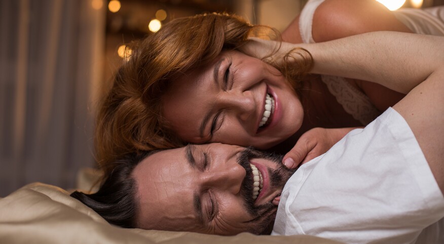 Man and woman cuddling and smiling in bedroom